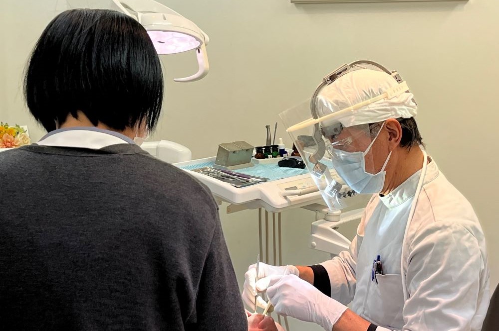拡大鏡（ルーペ）を装着し、精密で正確な歯科治療を行う院長